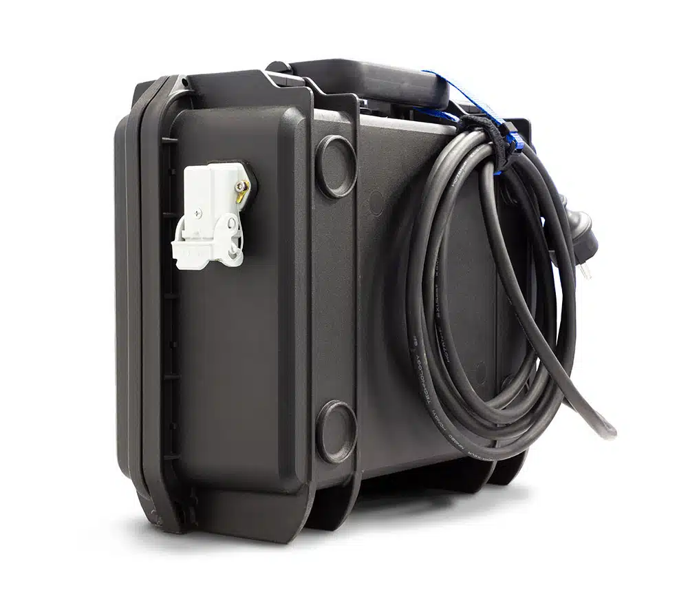 Das Bild zeigt einen robusten, schwarzen Hartschalenkoffer, der für den technischen oder industriellen Einsatz konzipiert ist. An einer Seite ist ein langes, aufgewickeltes Kabel befestigt, außerdem befindet sich eine weiße Steckdose oder Anschlussbuchse an der Seitenfläche des Koffers. Der Koffer steht aufrecht auf einem weißen Hintergrund.