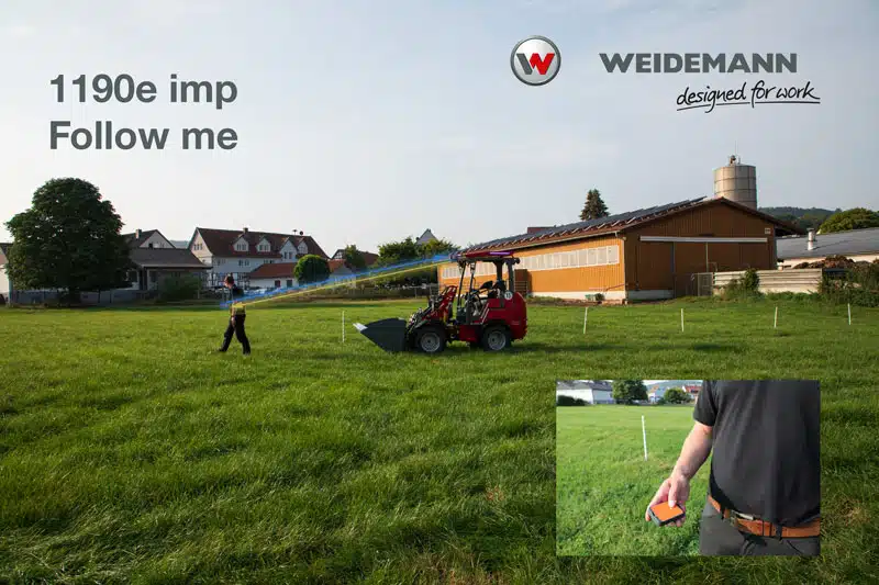 Das Bild zeigt eine Grünfläche mit einem kompakten, roten Weidemann Radlader, der einer Person folgt. Im Hintergrund sind landwirtschaftliche Gebäude und ein Silo zu sehen. Links oben steht der Text „1190e imp Follow me“ sowie das Logo von Weidemann. Im Bild unten rechts ist eine Nahaufnahme einer Hand mit einer Fernbedienung am Gürtel eingeblendet, die vermutlich zur Steuerung des Radladers dient.